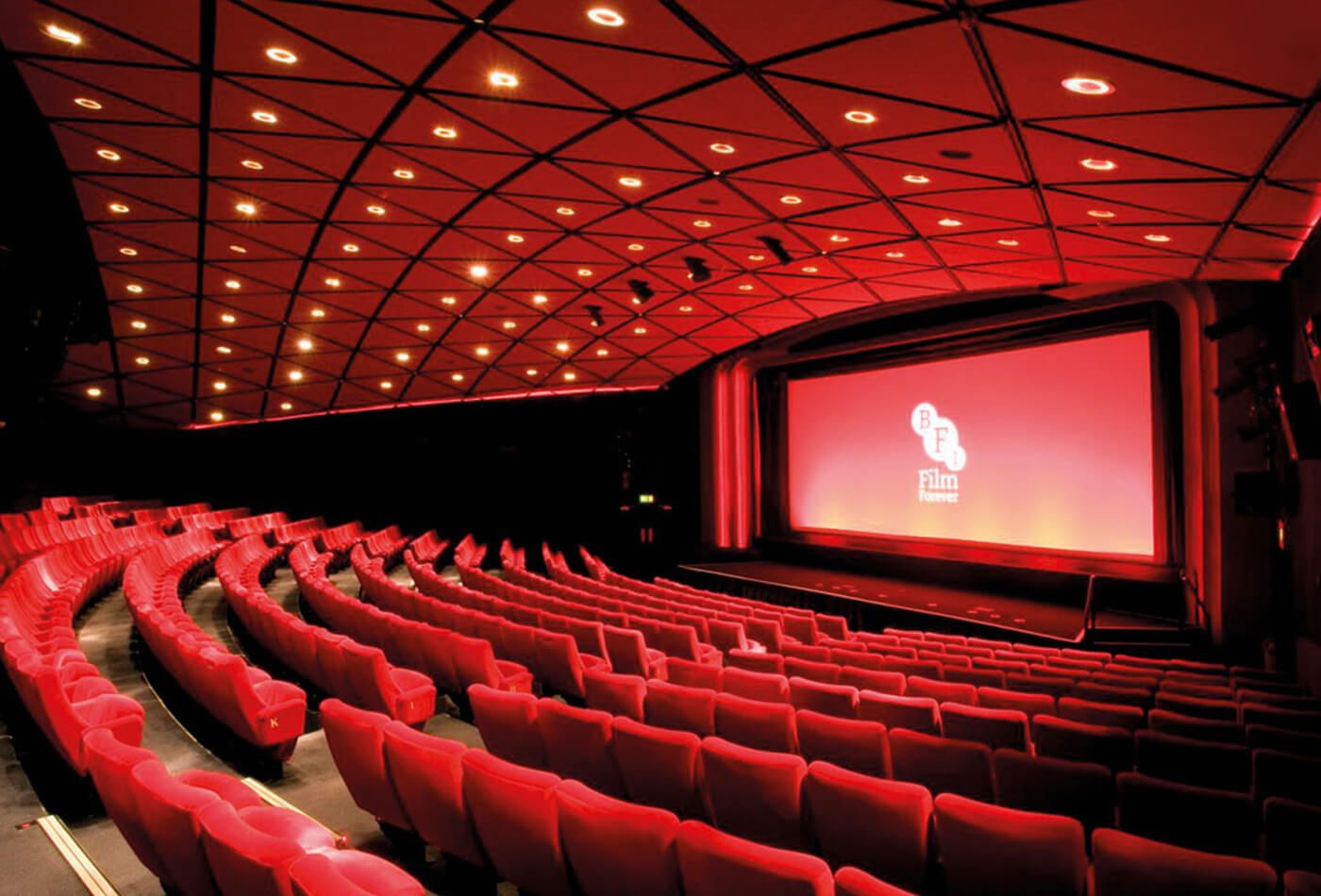 Interior shot of red velvet seats and stage with a red screen