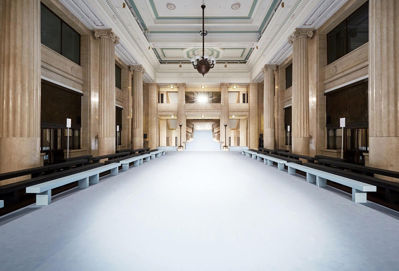 Long white runway with extremely high ceilings, greek columns and seating along each side