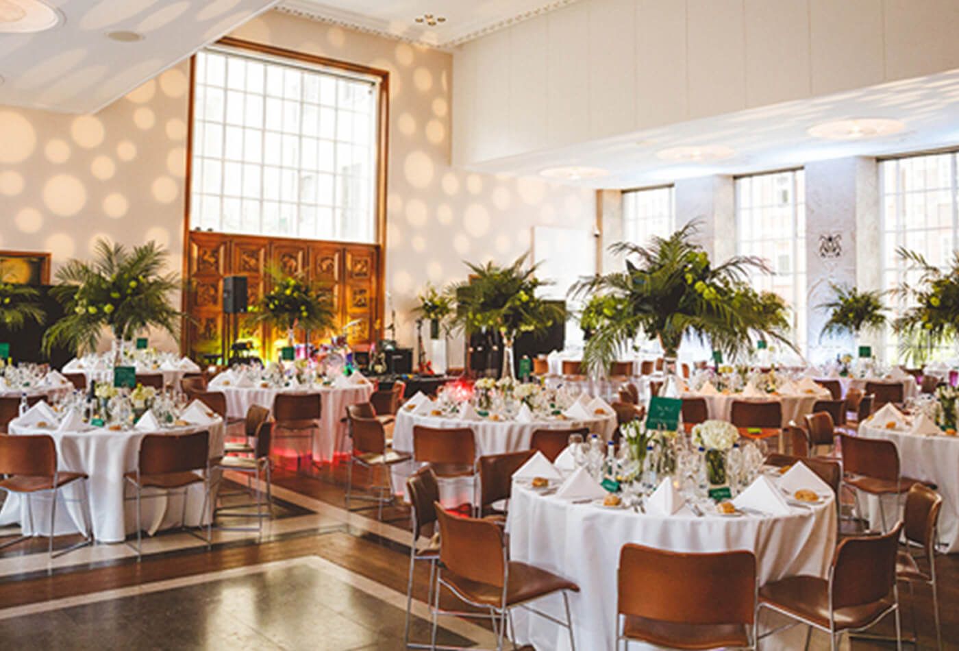 White wedding with brown leather chairs, tall plants and abstract patterns projected onto the wall