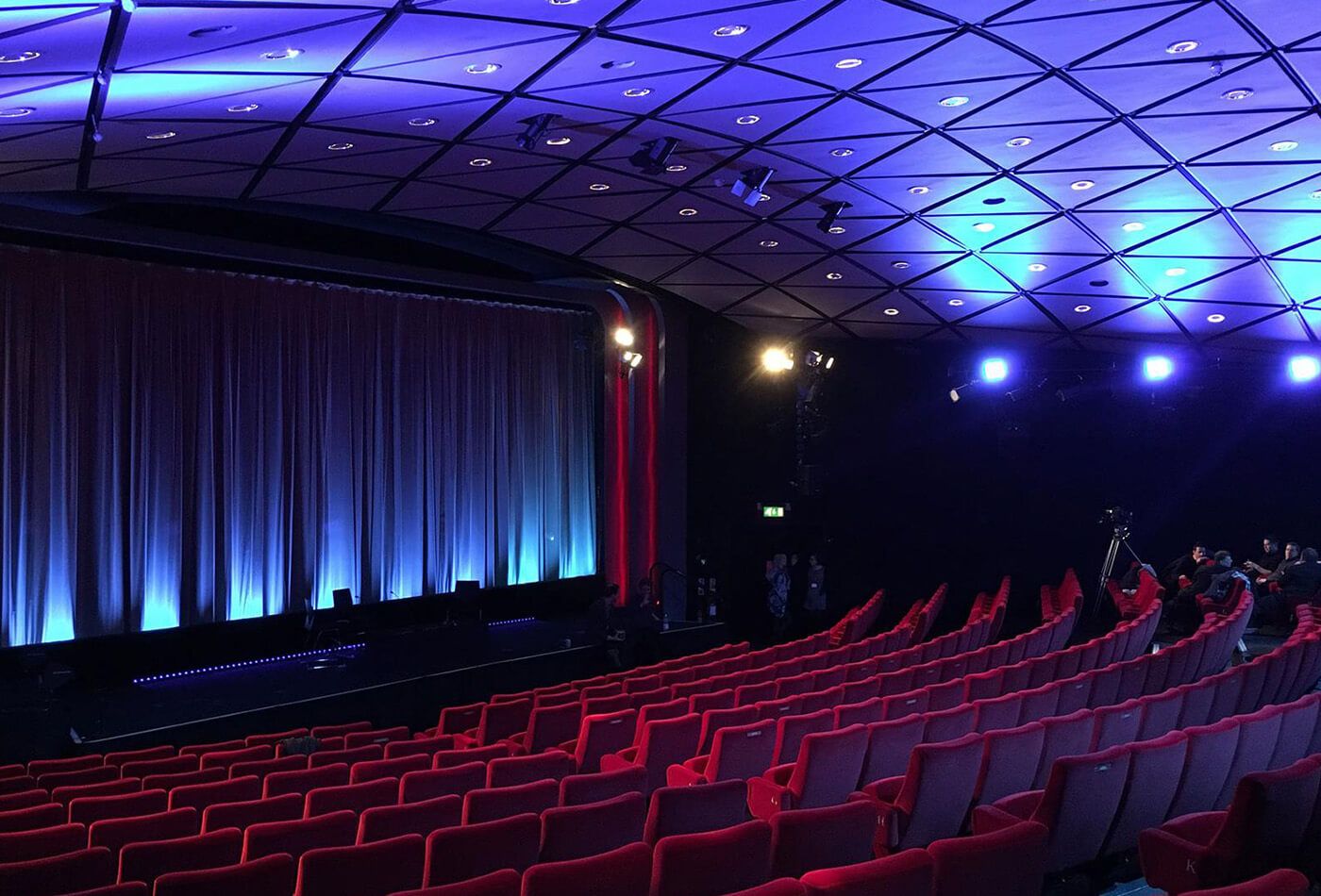 Interior shot of red velvet seats and stage lit up in blue